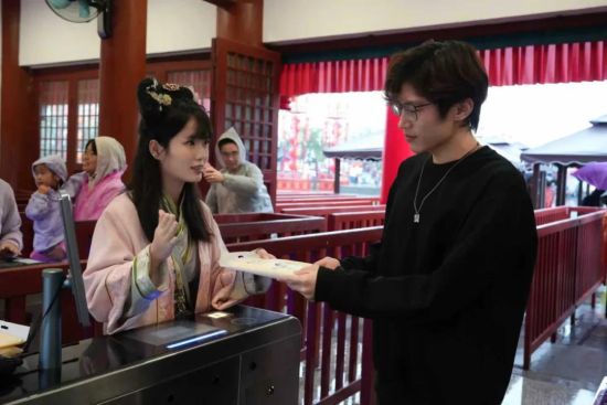 图为工作人员在为游客发放雨衣。 图为工作人员在为游客发放雨衣。