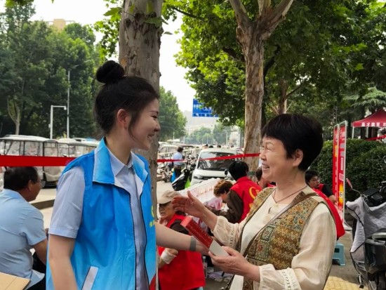 图为平顶山市一高考考点外,青年志愿者为陪考家长送上清凉折扇。周子洋 摄 图为平顶山市一高考考点外,青年志愿者为陪考家长送上清凉折扇。周子洋 摄
